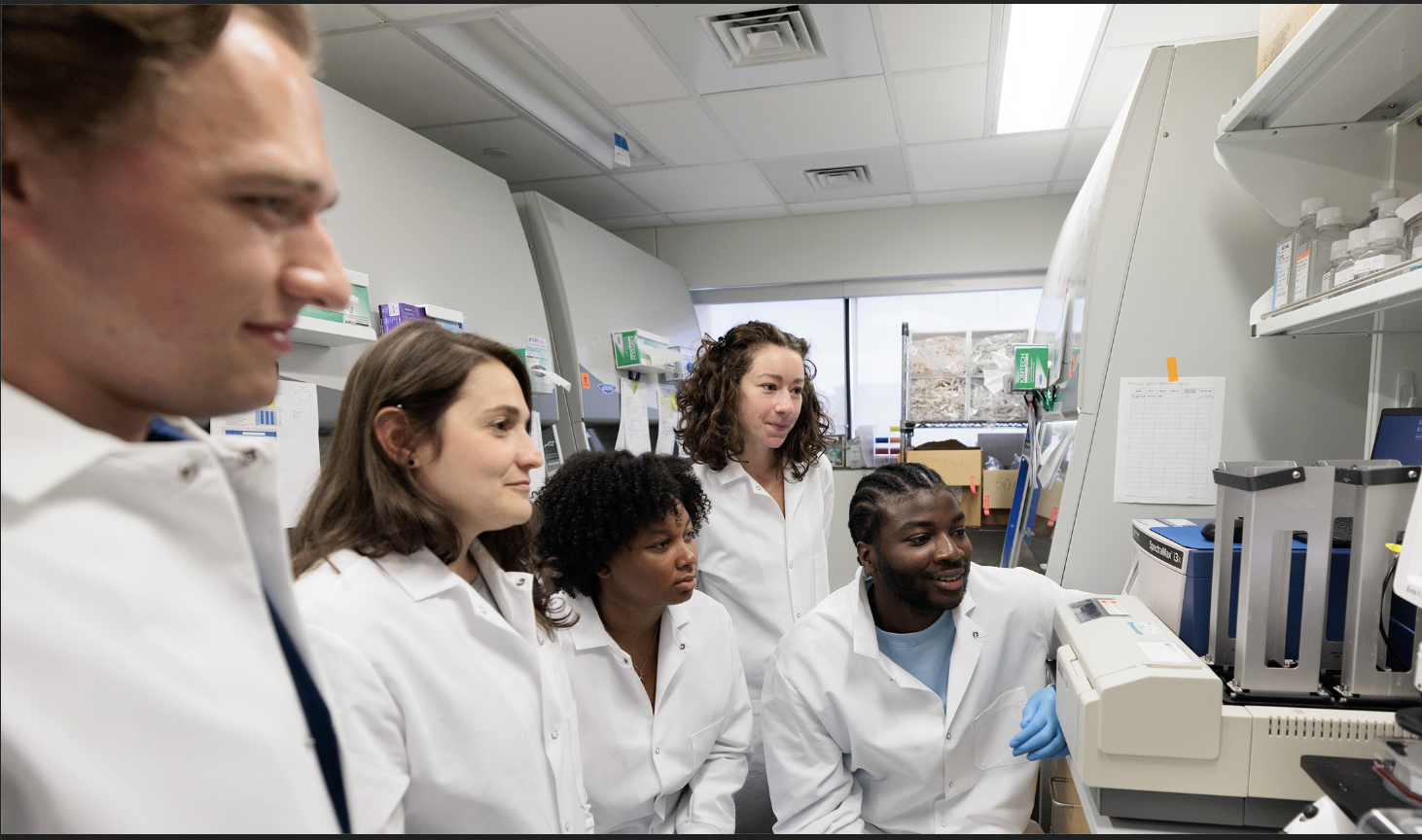 Four researchers looking at equipment within their lab