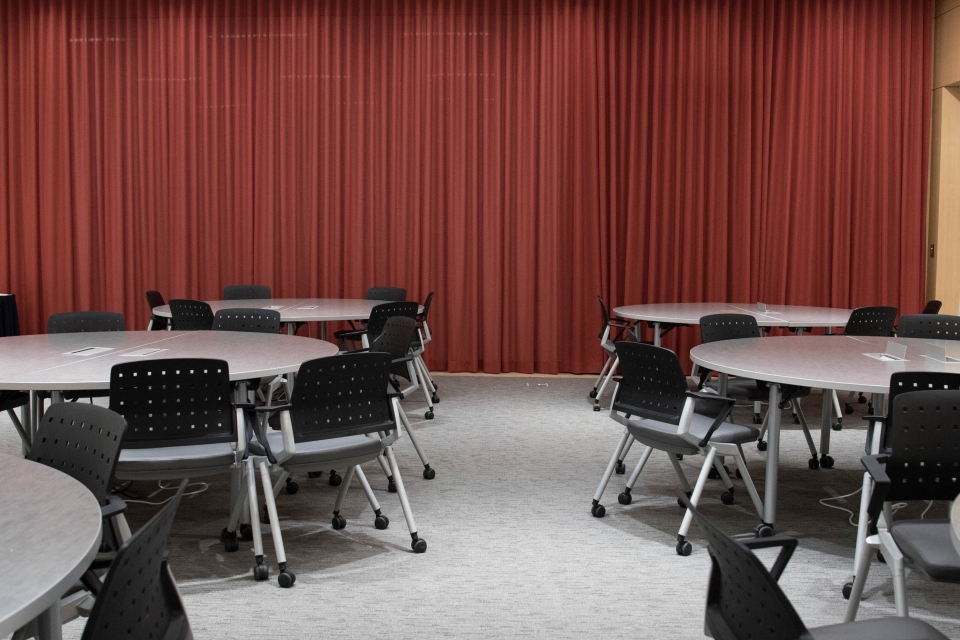Room with round tables, chairs, and a red curtain backdrop