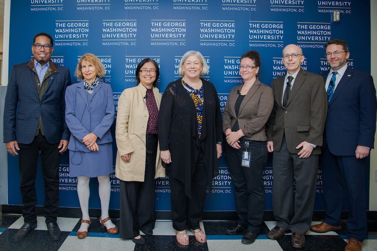 Moderator Dean Lach and panelists smiling with GW President Ellen Granberg