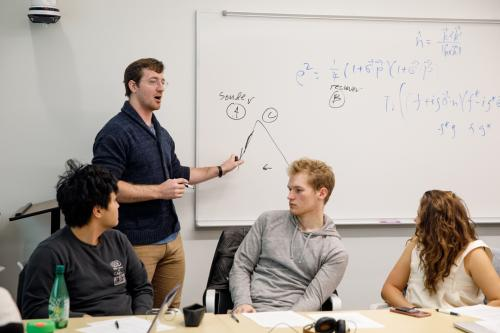 Professor and three students in physics classroom