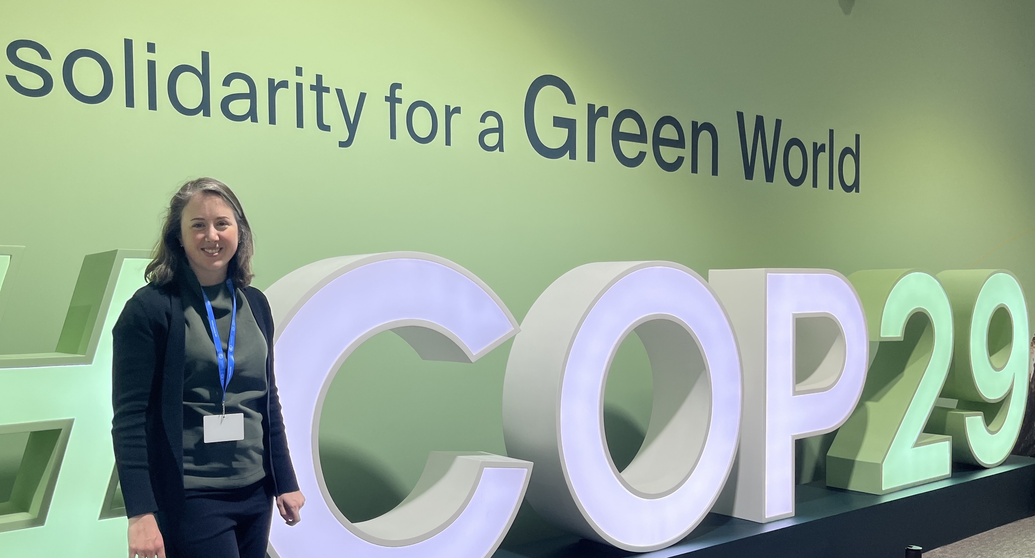 Professor Grady stands in front of a #COP29 sign at COP29 in Baku, Azerbaijan.