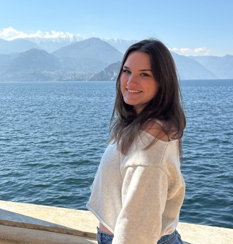 Grace Z in a white shirt standing by a waterfront