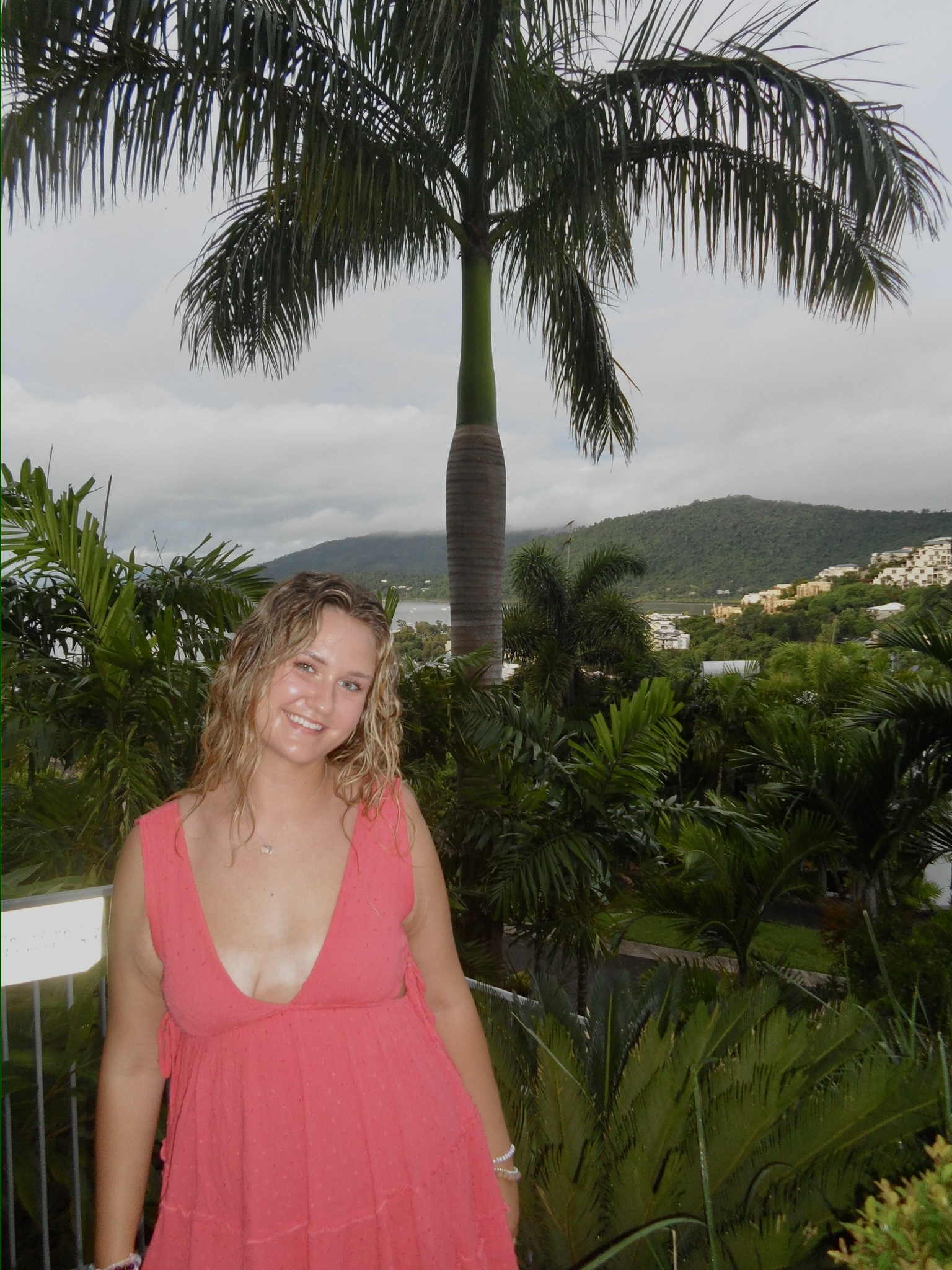 Maddie in a pink dress in front of a palm tree