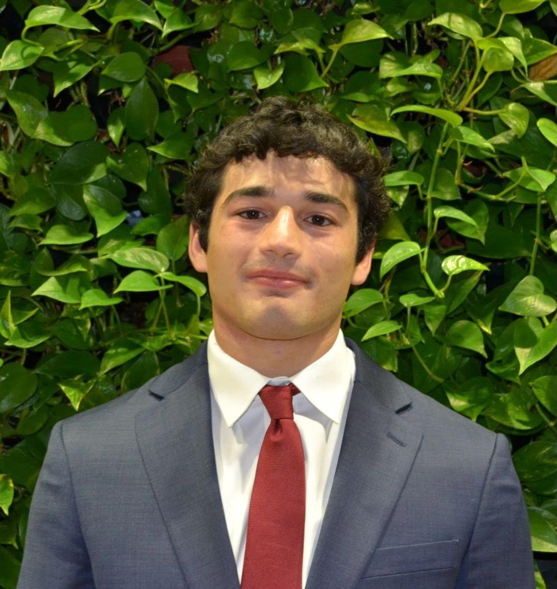 Headshot of Luca in a grey suit and red tie