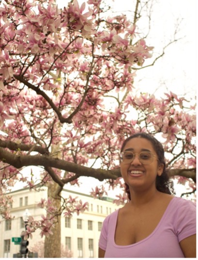 Student in pink top by a cherry blossom tree