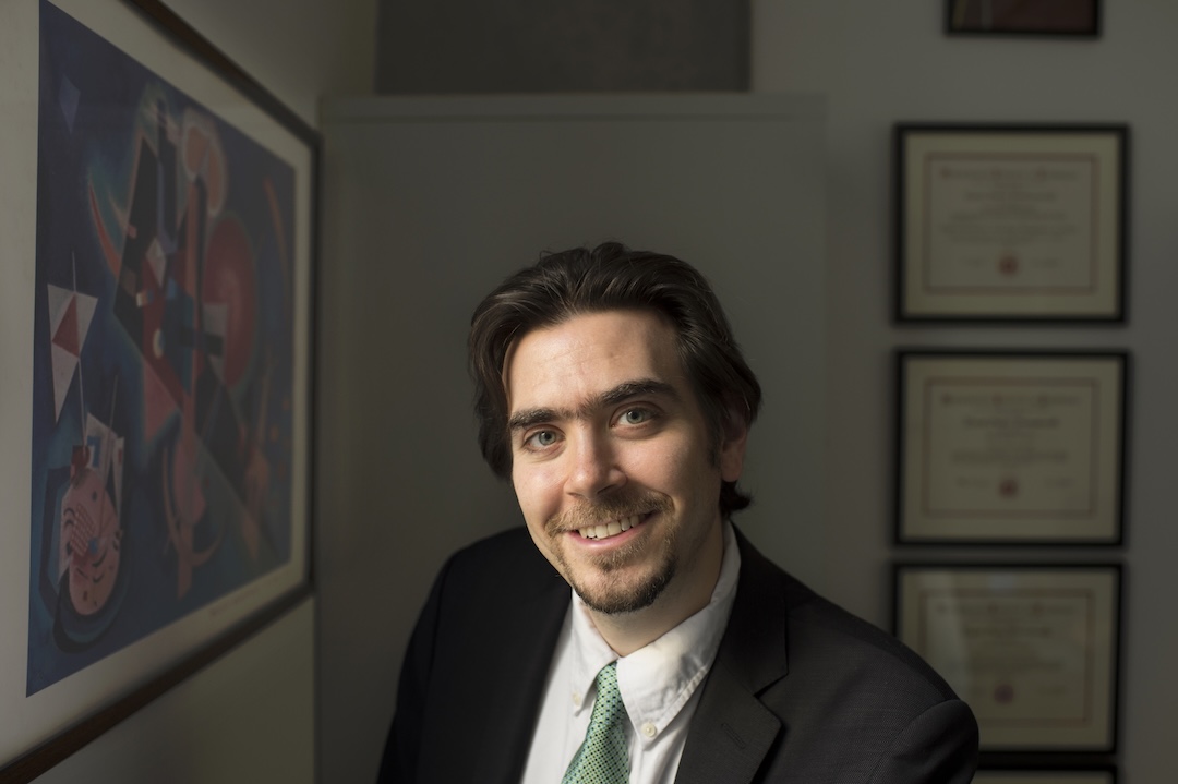 Professor in a black blazer, white shirt and green tie