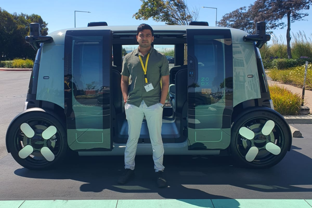 Shrey Patel in front of Zoox's autonomous vehicle