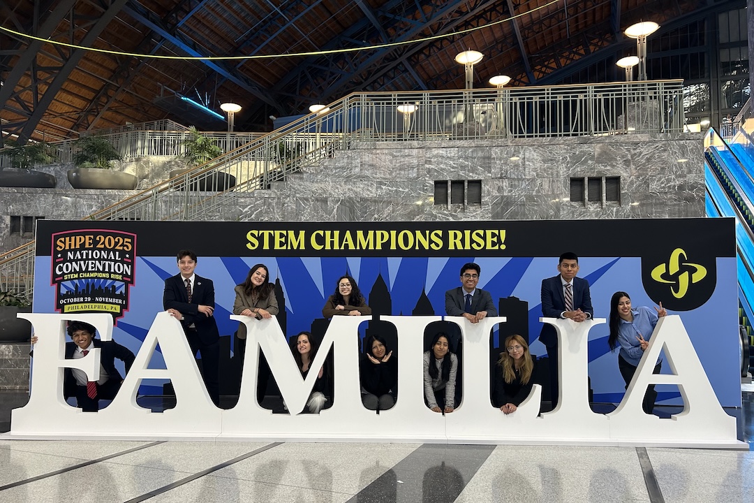 Student taking a picture behind a FAMILIA sign