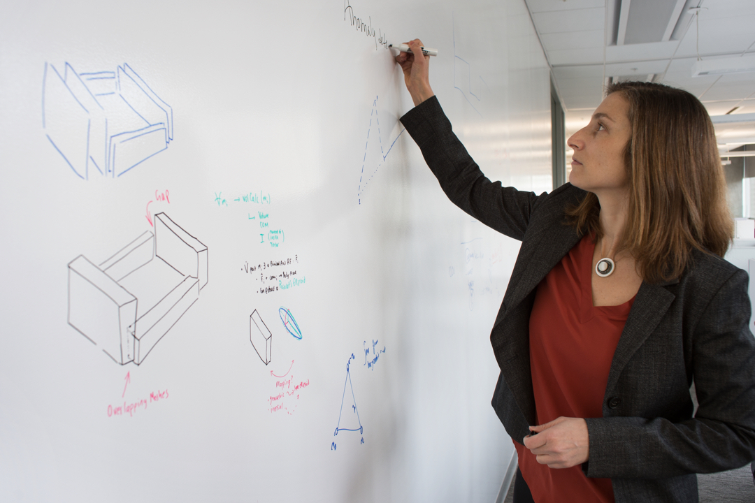 Claire Monteleoni in front of a dry erase board with equations