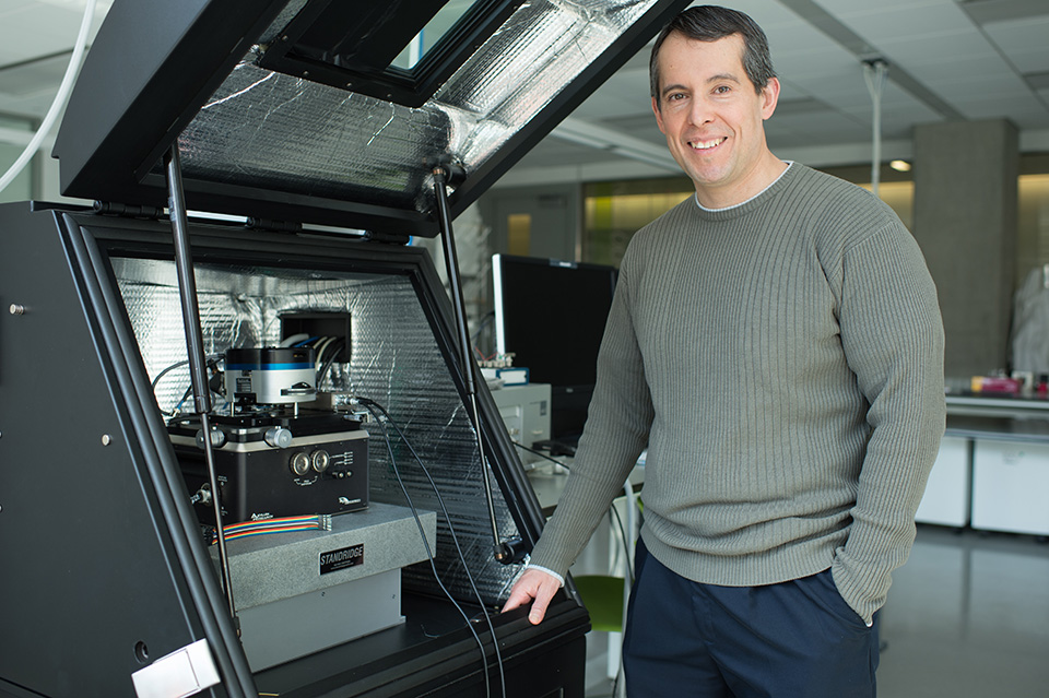 GW Pinpoint; An Engineer's Friend; photo of professor in front of lab equipment