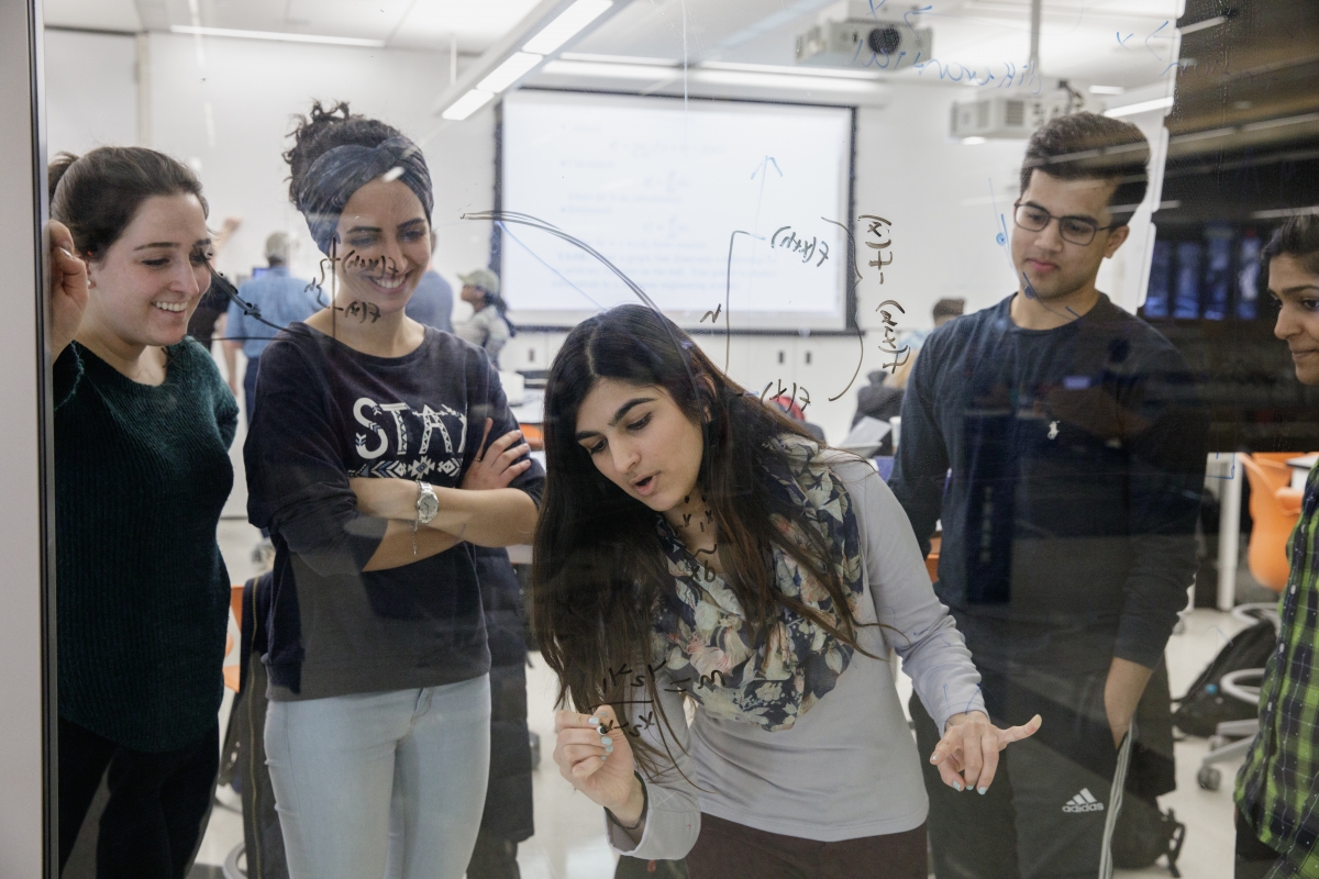 Students solving equations on glass wall