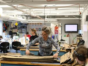Artist Celia Ledón and students in the GW Innovation Center cutting cardboad