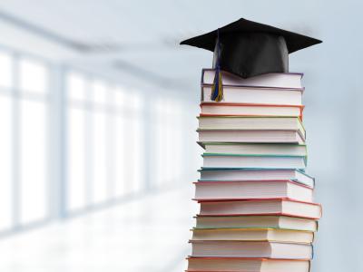 Stack of books with graduation cap on top