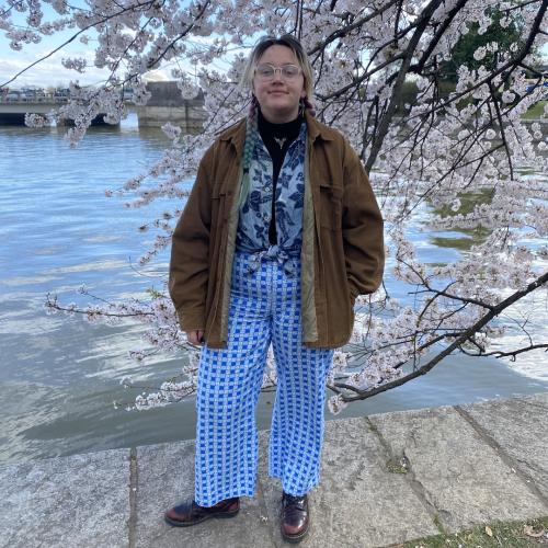 Student standing by a cherry blossom tree