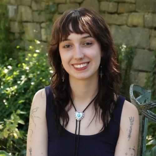 Female stand in front of a wall and bushes