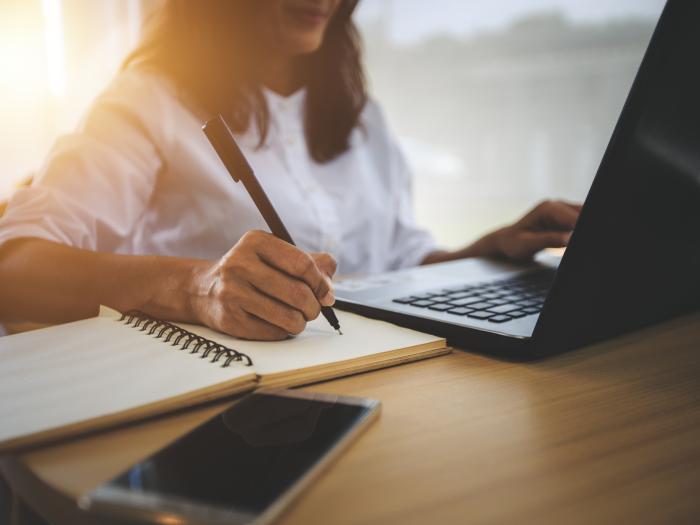 Women writing and working on laptop